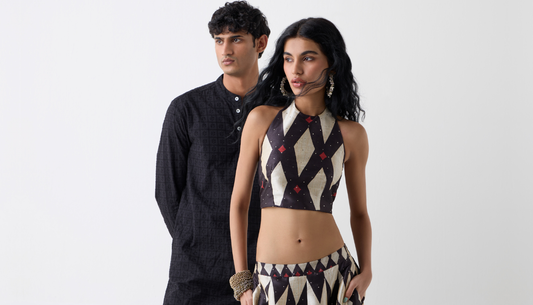 Man and woman in festive Indian outfits posing at a wedding venue